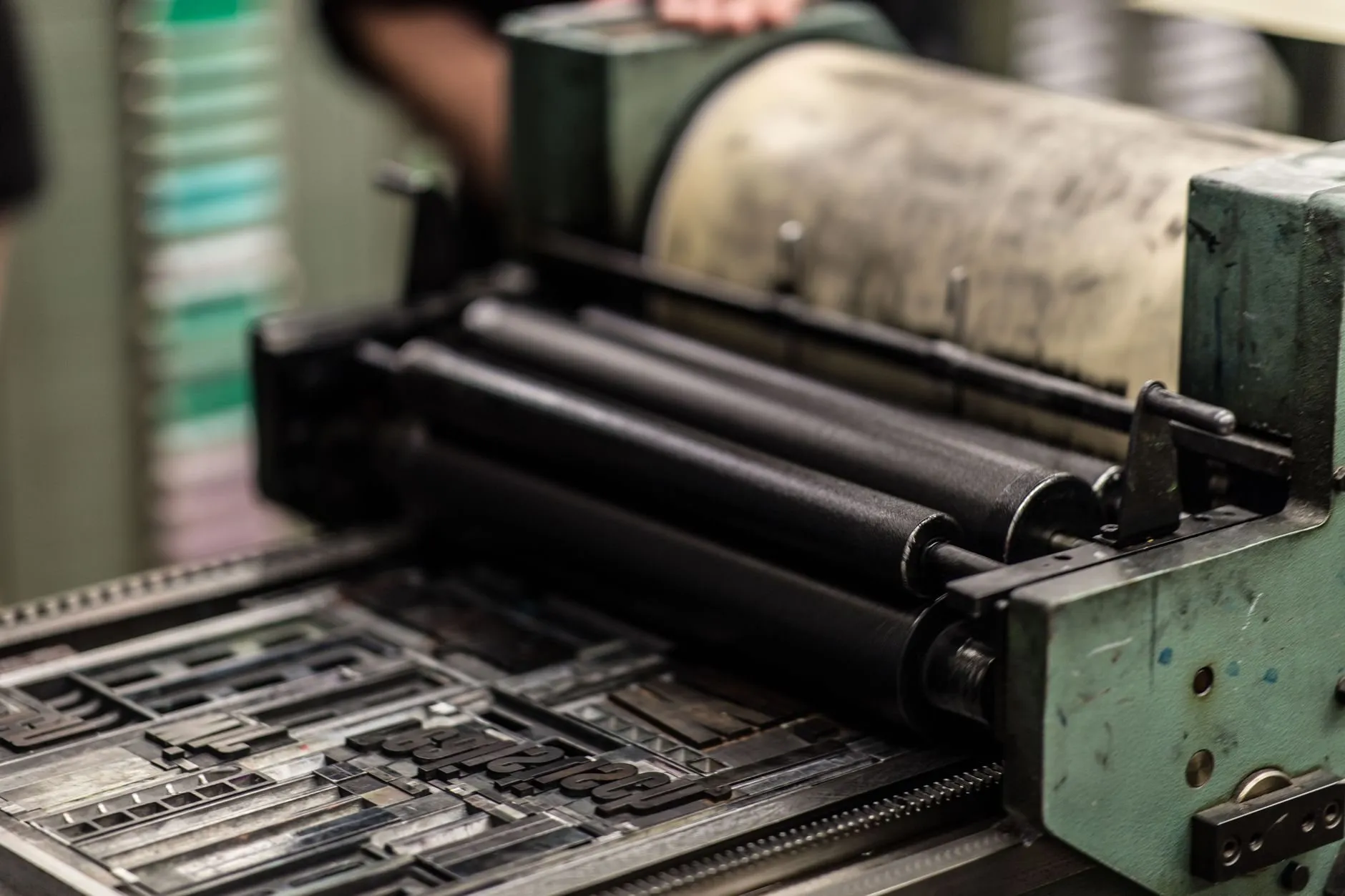 Inked rollers of a proofing press running over a forme of metal type