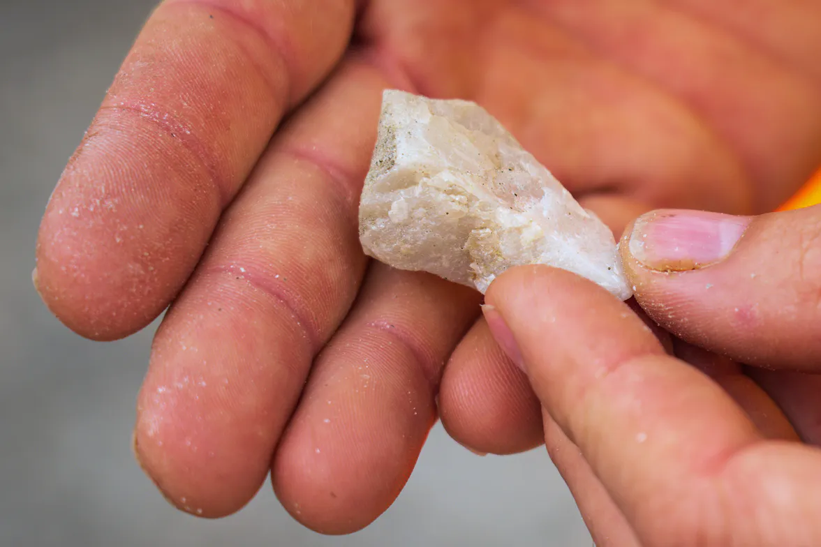 Two hands turning a pale broken stone to look at the fresh face.