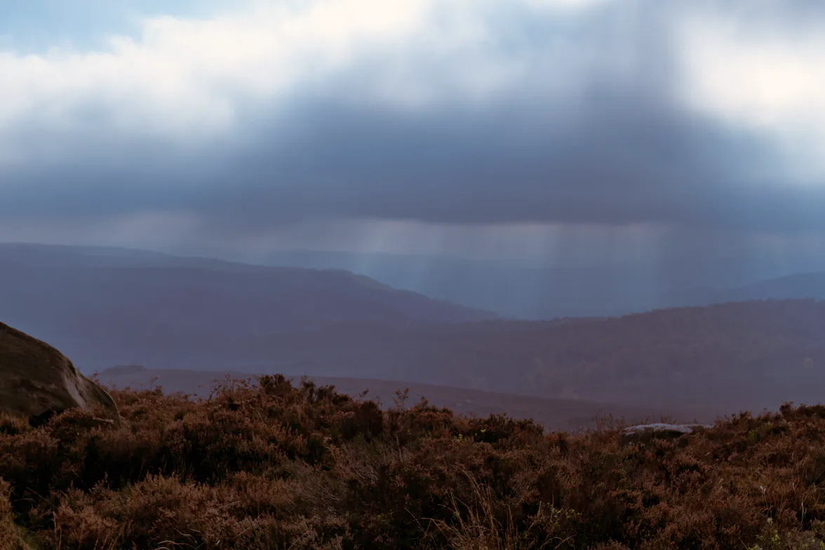 Open moorland under a rain squall, the far side of the valley lost in the shower.