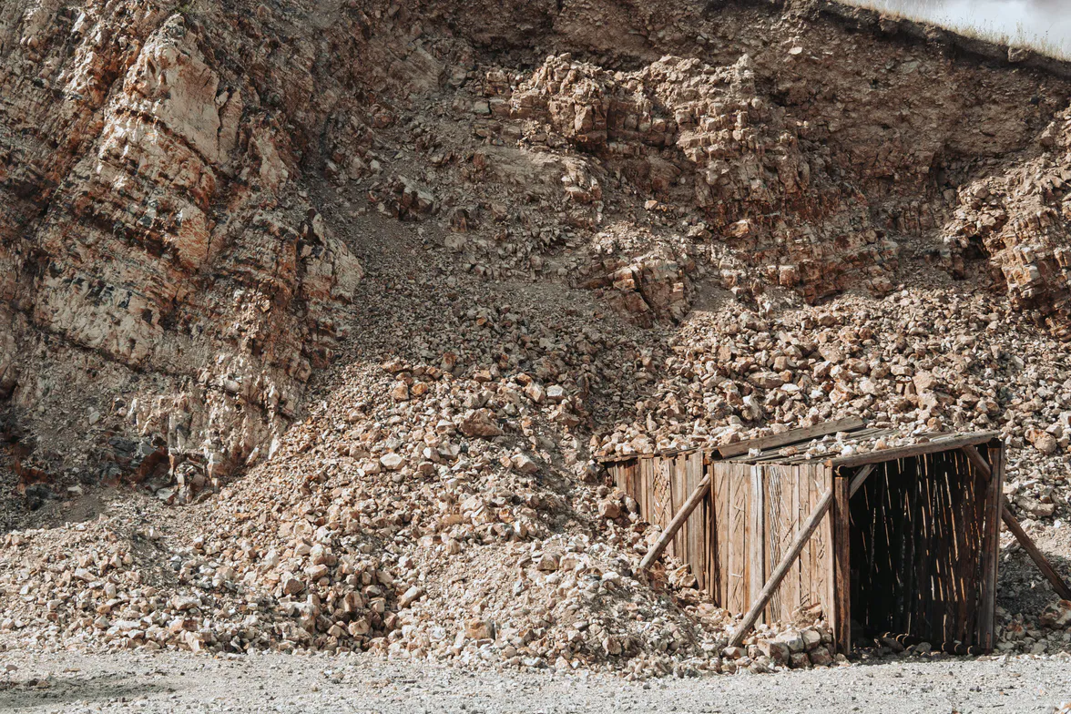 A timbered adit mouth at the foot of a cutting, closed with boards.