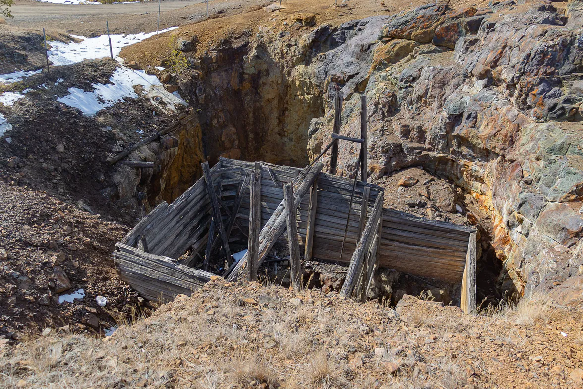 Collapsed mine timbering in a cutting, with snow still lying in the shaded side.