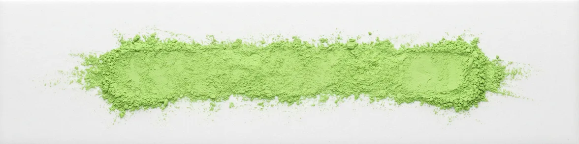 A broad horizontal smear of apple green powder drawn across a white porcelain streak plate.