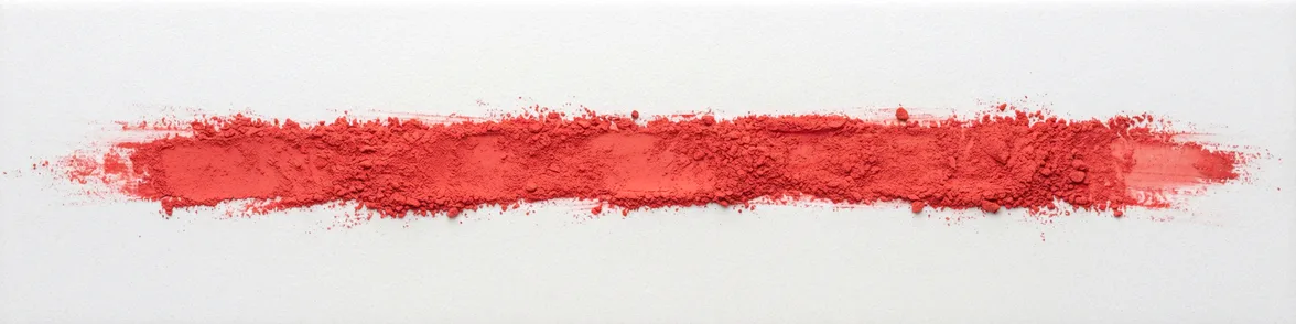A broad horizontal smear of scarlet powder drawn across a white porcelain streak plate.