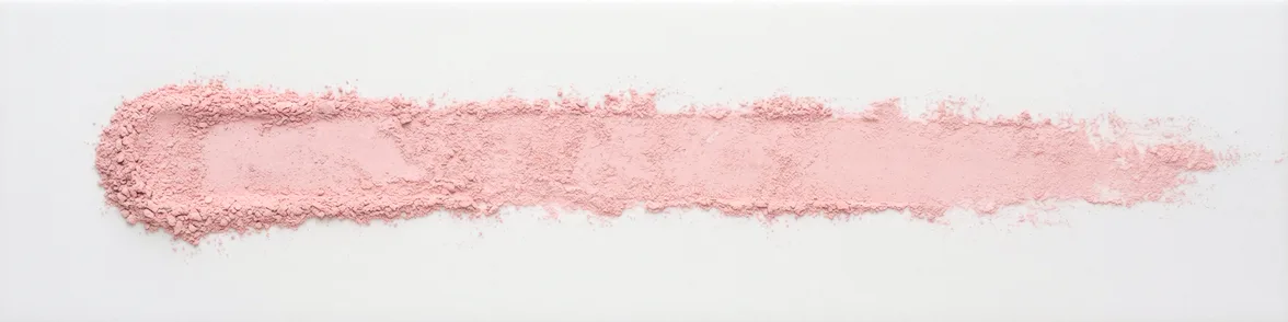 A broad horizontal smear of pale crimson powder drawn across a white porcelain streak plate.