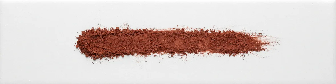 A broad smear of red-brown powder drawn across a white porcelain streak plate.