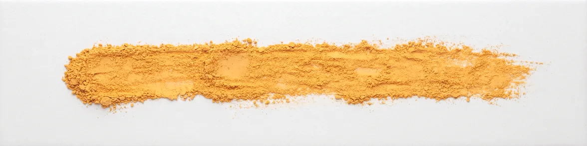 A broad horizontal smear of orange-yellow powder drawn across a white porcelain streak plate.