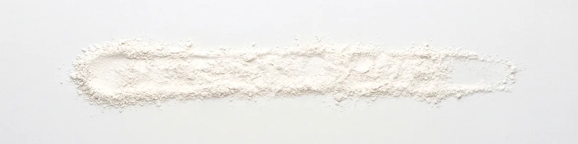A broad horizontal smear of white powder drawn across a white porcelain streak plate.