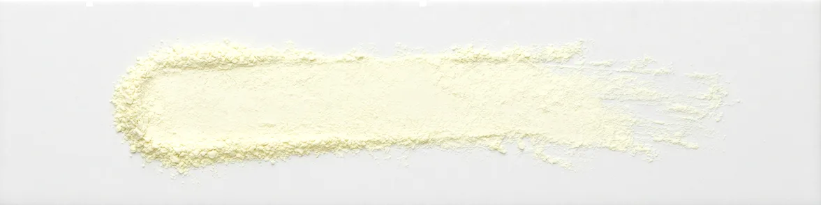 A broad horizontal smear of pale yellow powder drawn across a white porcelain streak plate.